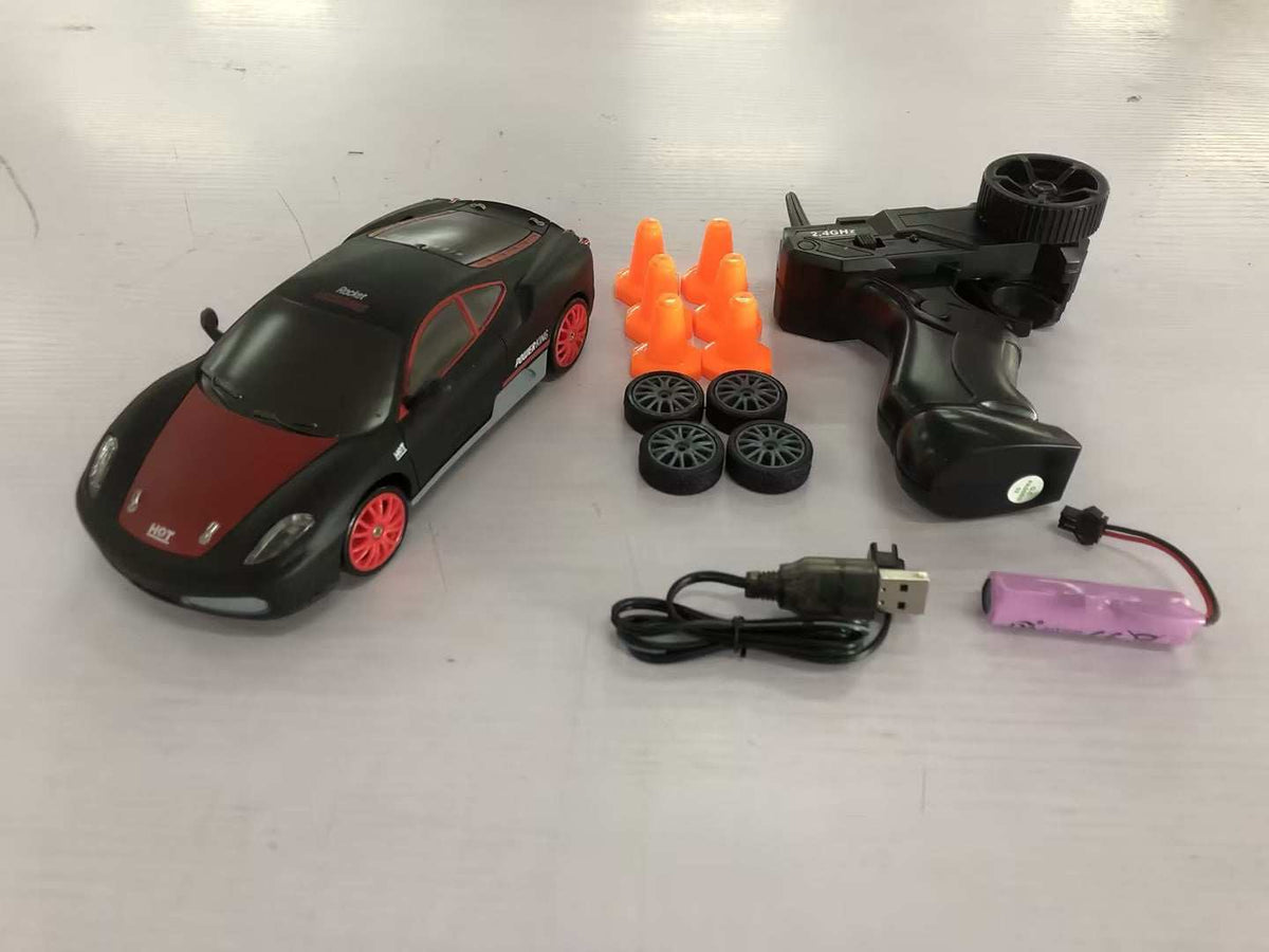 4WD RC Drift Car in black with a red hood, red wheels, remote control, orange cones, spare tires and battery