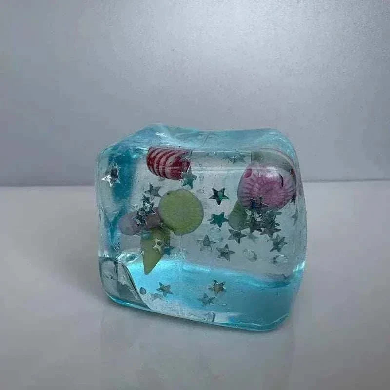 Squishy Ocean Fidget stress ball in translucent blue gel with colorful sea creatures, shells, and star shapes