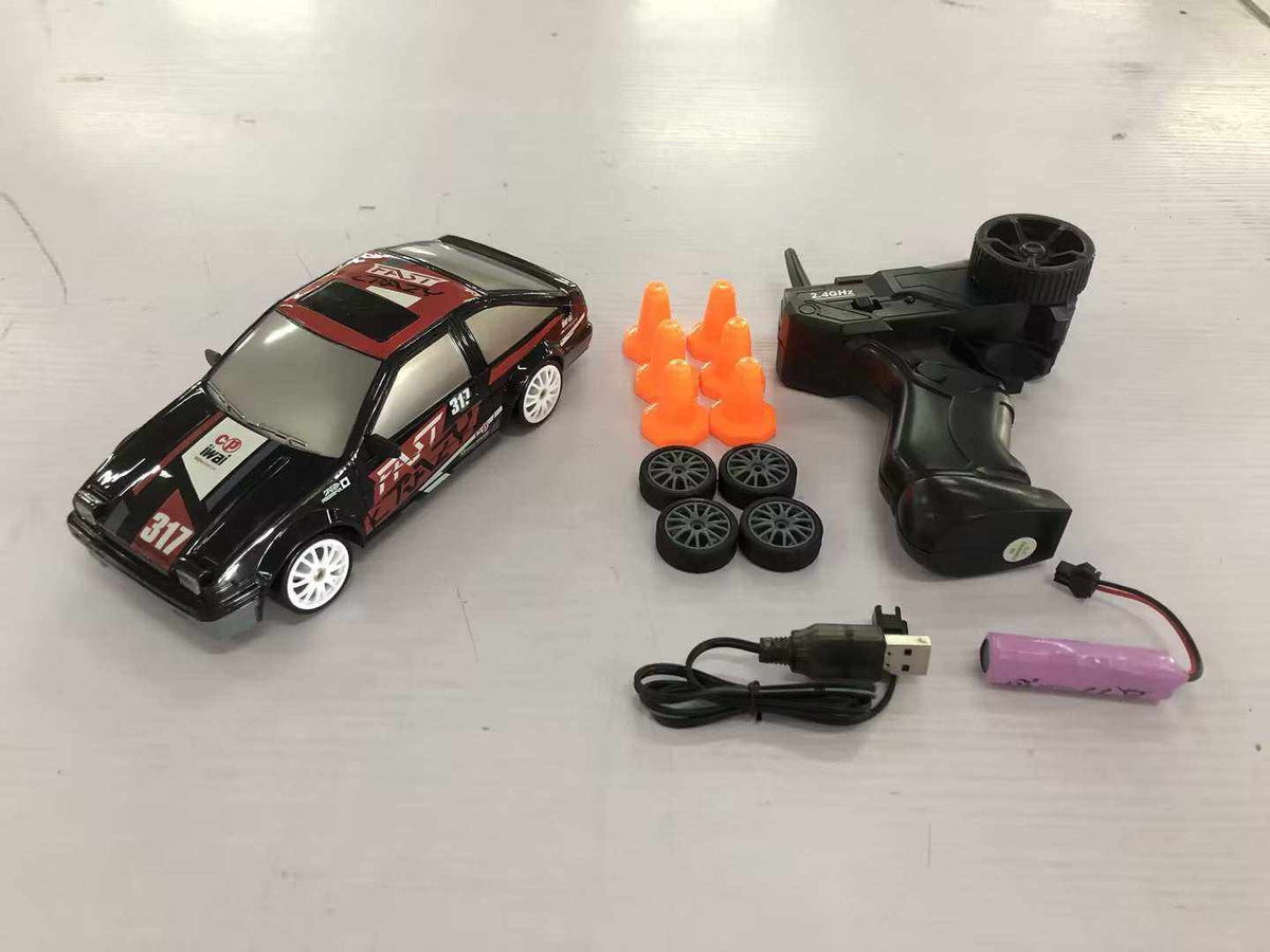 4WD RC Drift Car in black with red racing decals, white wheels, and a remote, spare tires, cones, and accessories