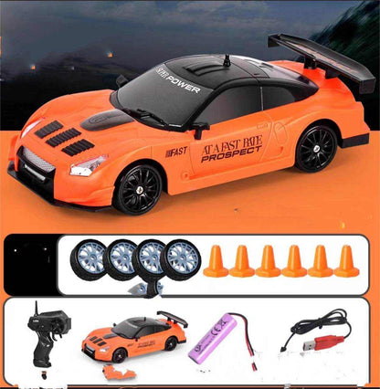 4WD RC Drift Car in bright orange with black roof, racing graphics, rear spoiler, plus spare wheels and cones