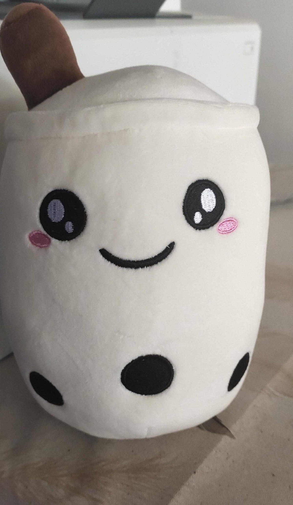 Bubble Tea Plush Pillow in a white plush cup shape with embroidered smiling face, pink cheeks, brown straw and black tapioca pearls